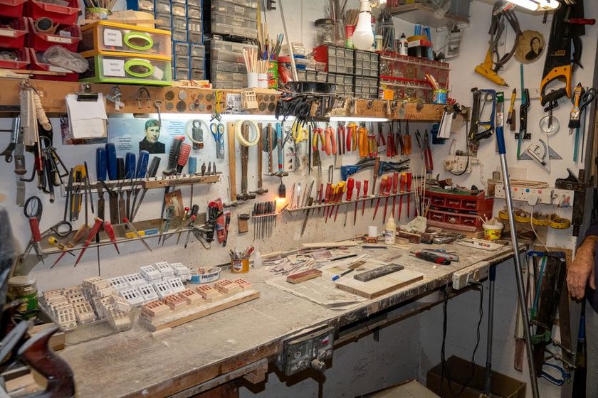 A pegboard wall of hand tools, each hung over its own painted outline